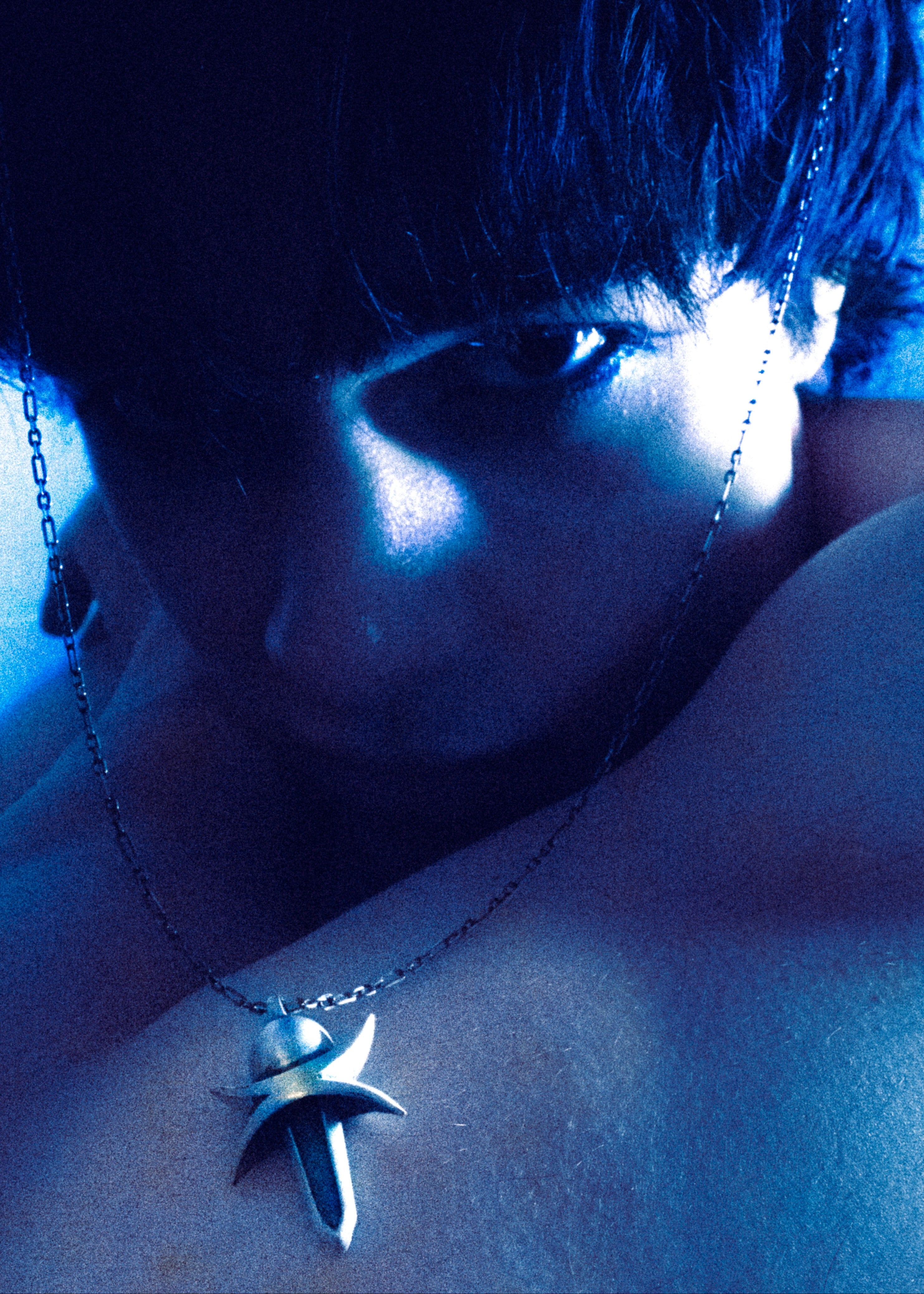 Close-up of a person wearing a silver necklace with a star pendant.